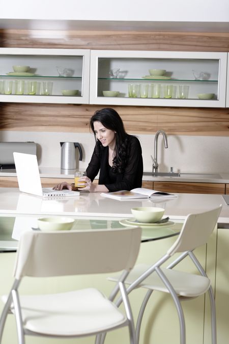 Attractive young woman using her laptop in the kitchen