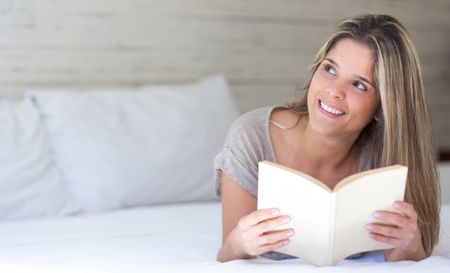 Thoughtful woman enjoying reading a book at home