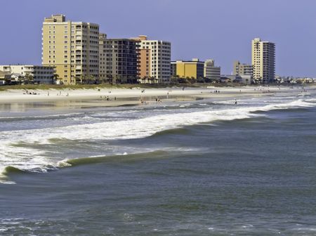 Vacation lifestyle: Surf, sand, and high-rise skyline along shore of Jacksonville Beach, Florida, on a sunny afternoon