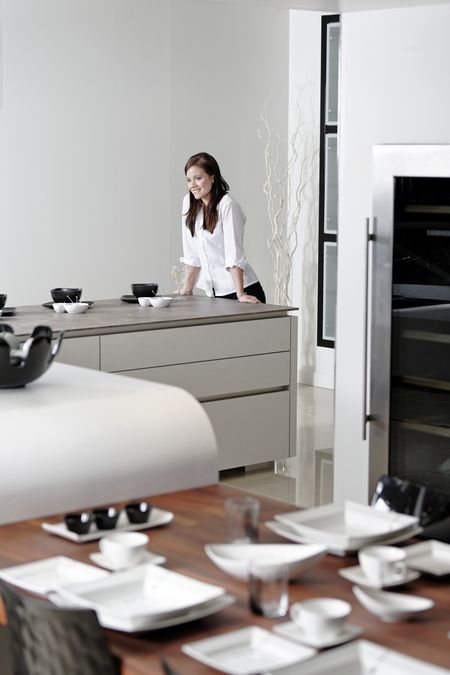 Beautiful young woman relaxing in her elegant white kitchen