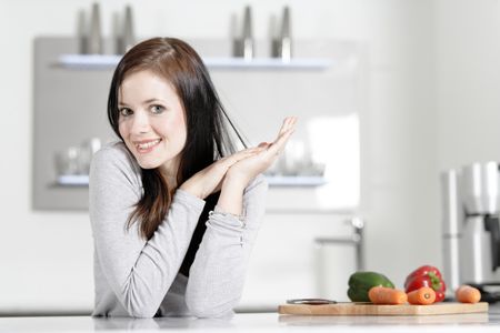 Attractive young woman in her elegant kitchen with fresh vegetables ready to cook.