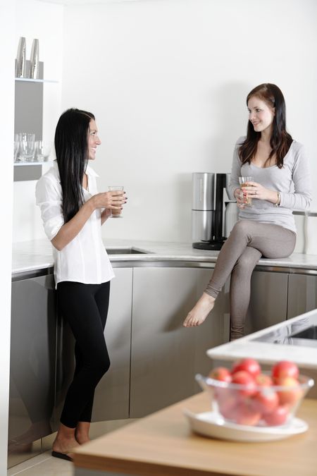 Two friends catching up over coffee in their kitchen.