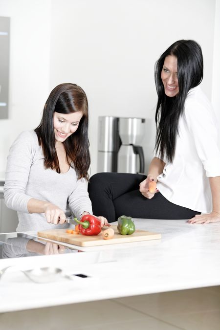 Two attractive friends preparing food in their kitchen at home.