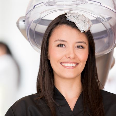 Woman in a beauty salon dying her hair and smiling