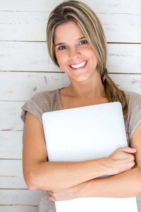 Woman carrying her laptop and looking very happy