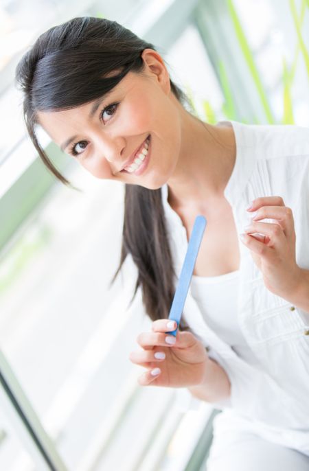 Beautiful woman filing her nails and smiling