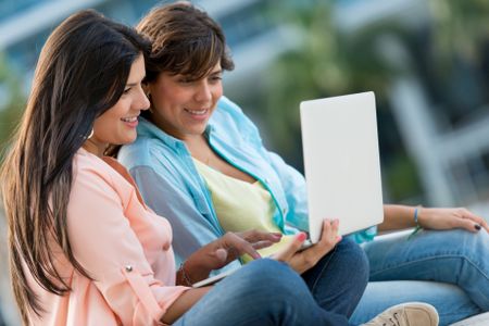 Happy girls with a laptop computer outdoors