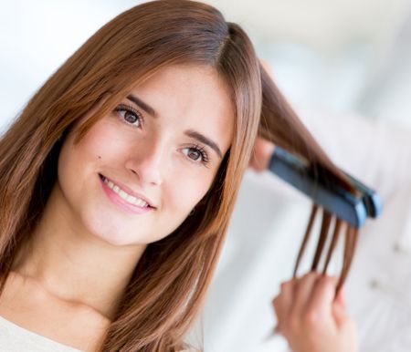 Woman straightening her hair at the beauty salon