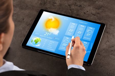 Business woman checking weekly weather forecast on tablet