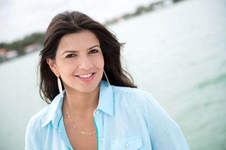 Portrait of a beautiful casual woman smiling by the sea