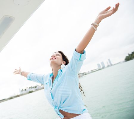 Woman in a yacht with arms open enjoying her freedom