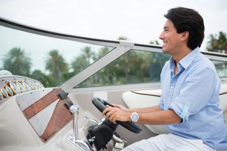 Handsome man driving a yacht looking very happy