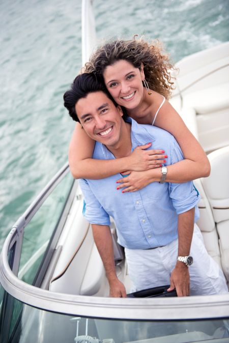 Beautiful couple hugging on a yacht looking happy