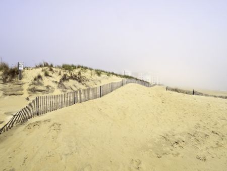 Coastal mirage: High-rises beyond sand dunes partially obscured by morning fog moving in from the Atlantic Ocean south of Virginia Beach, Virginia