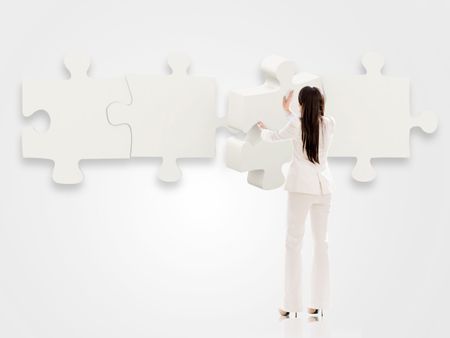 Business woman putting pieces of a puzzle together - isolated over white