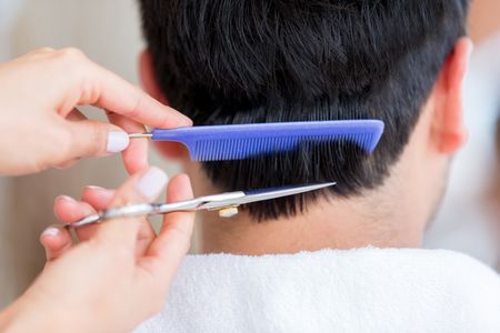 Stylist cutting hair of a man with scissors