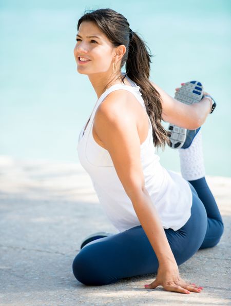 Beautiful woman stretching leg outdoors - fitness concepts