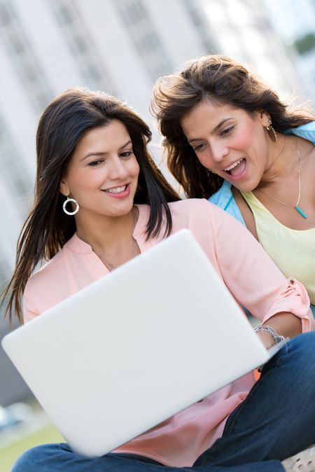 Female friends social networking on a laptop computer