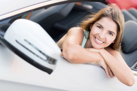 Woman in a convertible car looking very happy