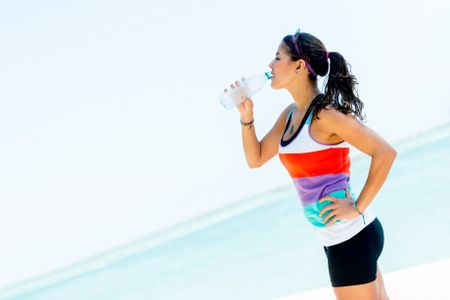 Sports woman drinking water from a bottle outdoors