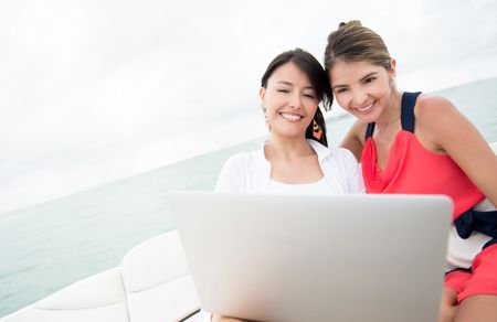 Happy women in a yacht with a laptop computer