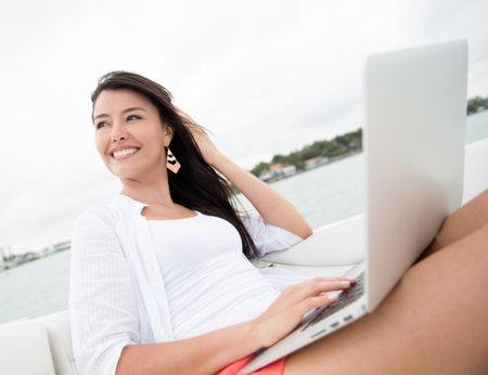 Woman social networking on a boat from laptop computer