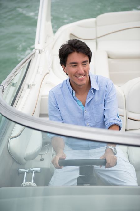 Handsome man driving a boat and enjoying the summer