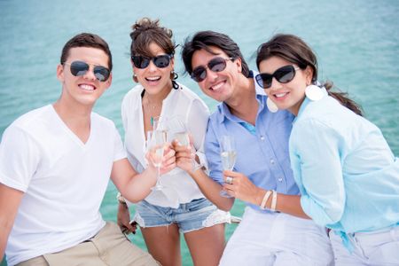Group of friends enjoying the summer drinking champagne and sailing