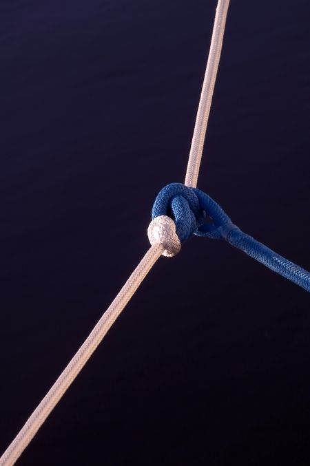 Blue nautical rope tied to white over dark water