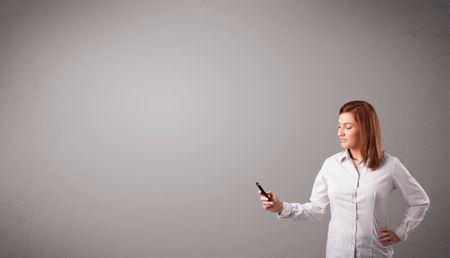 attractive young lady standing and holding a phone with copy space