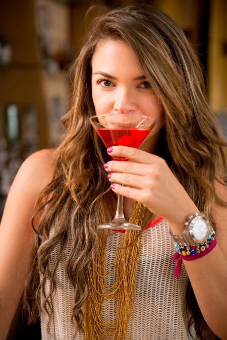Beautiful woman drinking a red cocktail at the club