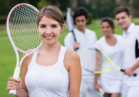 Female tennis player holding racket with her team at the background