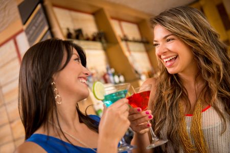 Two women having drinks at the bar looking very happy