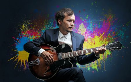 Young classical guitarist musician with colorful splotch wallpaper