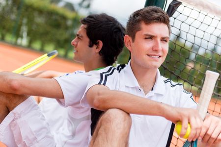 Male tennis players sitting at the court