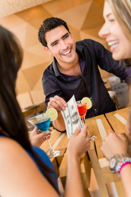 Group of friends paying for drinks at the bar with cash