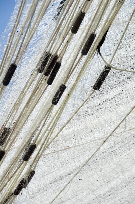 Dark floats in white fishing net hung to dry