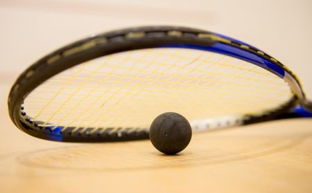 Squash racket with a ball at the court