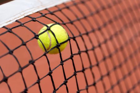 Tennis ball bouncing on the net at a clay court