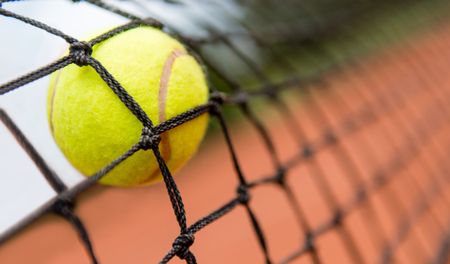 Tennis ball stuck on the net at a clay court