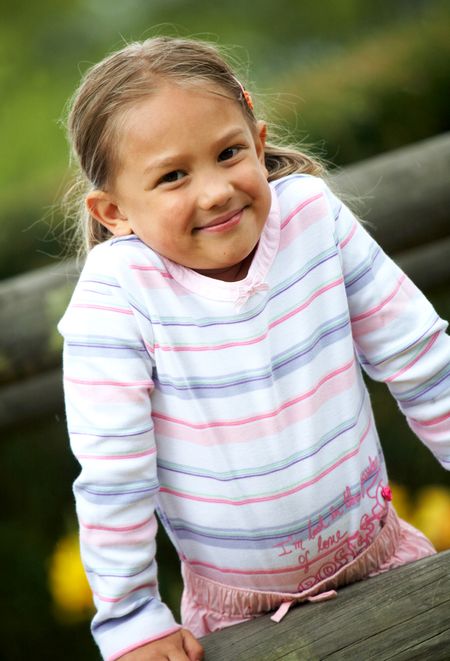 little girl portrait outdoors smiling over a wblue sky in the background