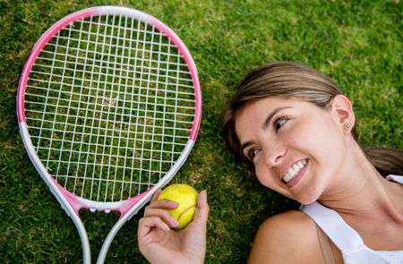 Tennis player lying on the floor with racket and ball - portrait