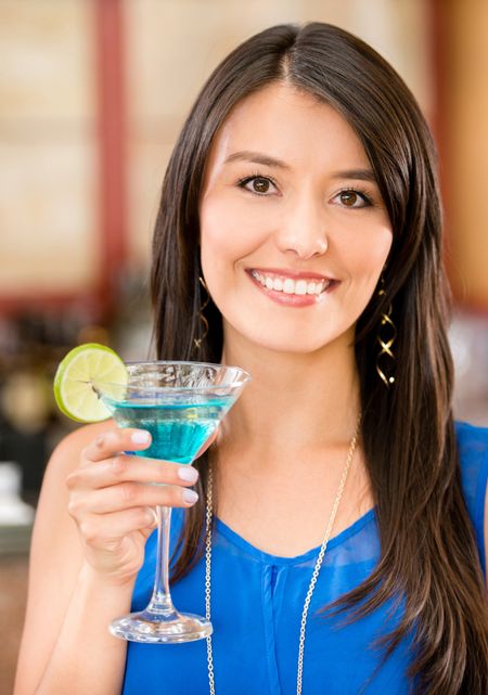 Happy woman drinking a cocktail at the bar