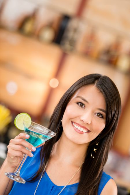 Woman drinking a martini at the bar and smiling
