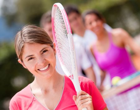 Happy woman at the tennis court smiling with a racket