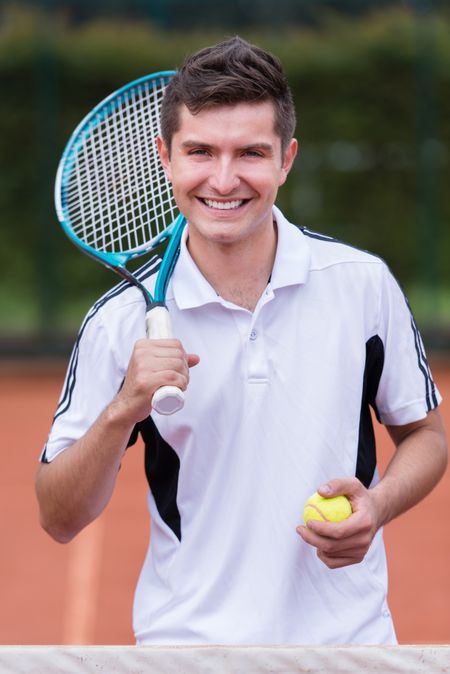 Happy male tennis player smiling at the court