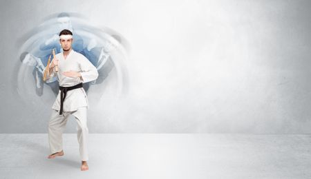 Young businessman in suit fighting with empty wall background