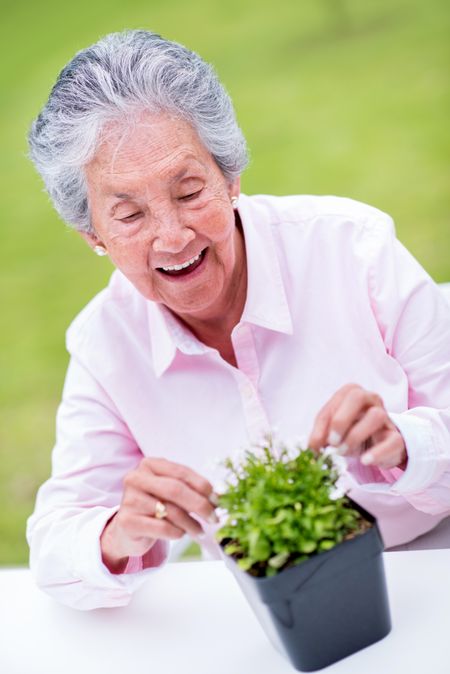 Beautiful senior woman gardening outdoors looking very happy