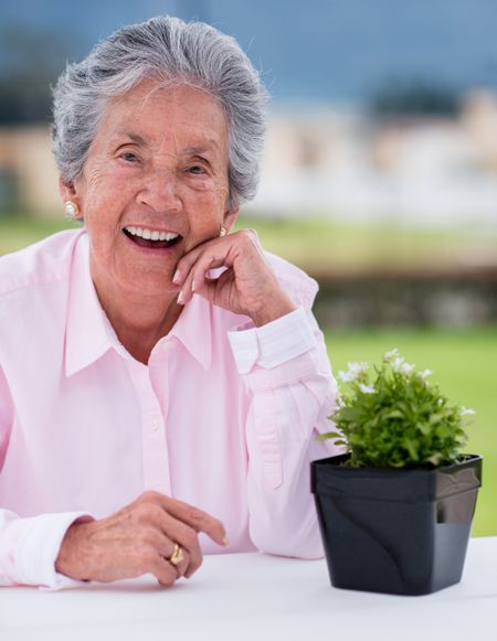 Happy elder woman with a plant enjoying outdoors