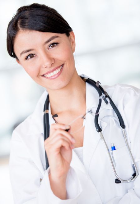 Happy female doctor smiling and holding glasses at the hospital